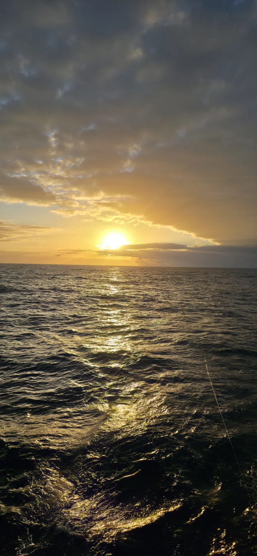 Sun breaking through dramatic clouds over the open ocean